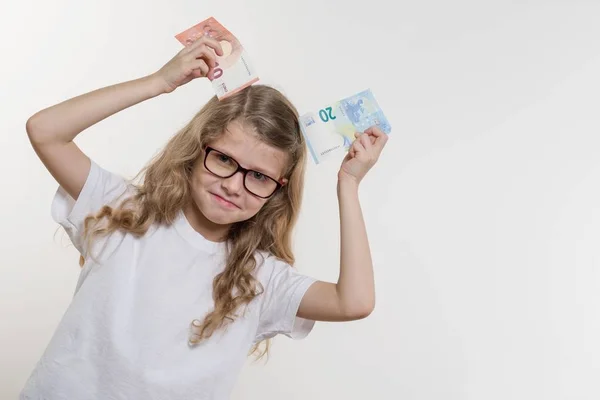Улыбающаяся маленькая девочка с деньгами, белым фоном, копировальным пространством. Деньги, финансы и концепция людей — стоковое фото