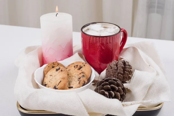 Karácsonyi hagyományos forró ital kakaós pillecukor és a cookie-kat a csokoládé csepp piros kupa, kúp, gyertya. — Stock Fotó