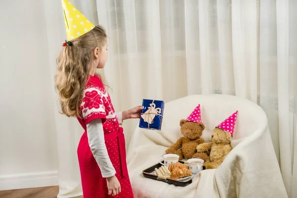 Fiesta de cumpleaños, niño en sombrero de fiesta jugando con osos de peluche . — Foto de Stock