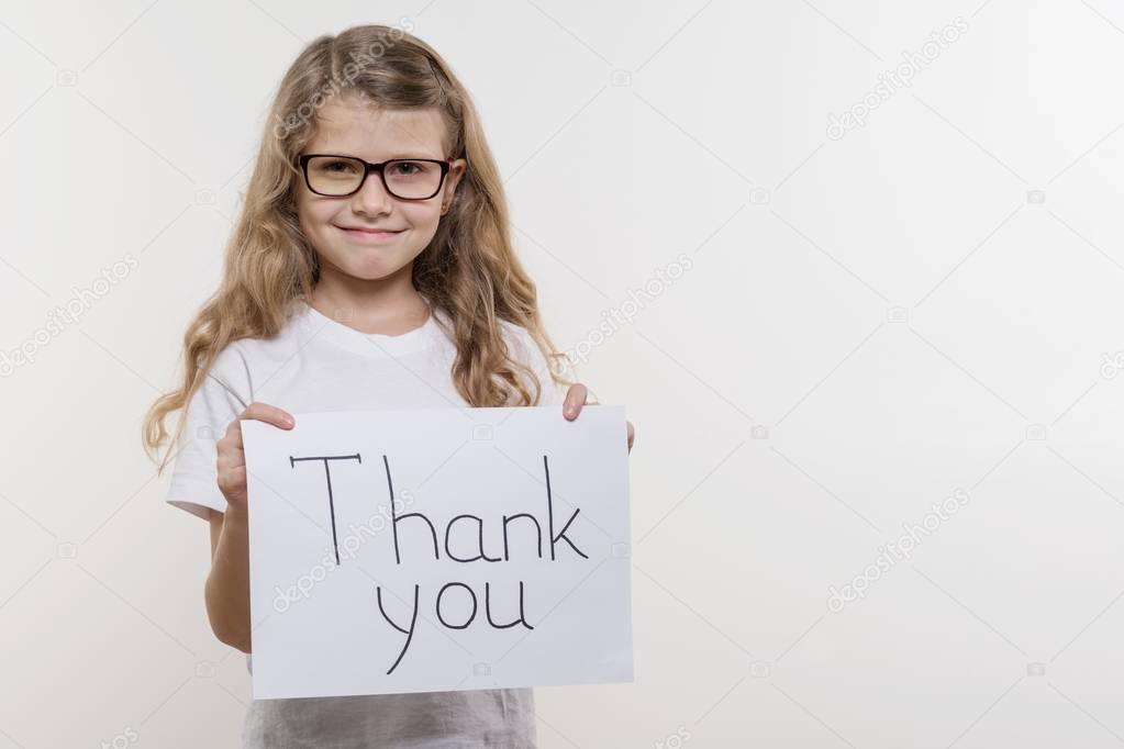 Girl child holding piece of paper with a word THANK YOU. White bakgrounde