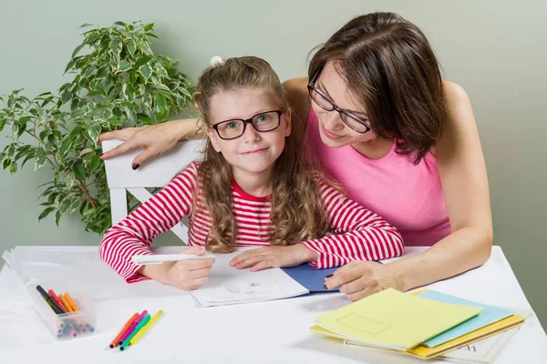 Mamá ayuda a su hija alumna de la escuela primaria en su cuaderno , — Foto de Stock