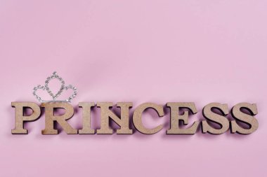 Word Princess abstract wooden letters. Pink background with sparkling crown. Textures, backgrounds, copy space clipart