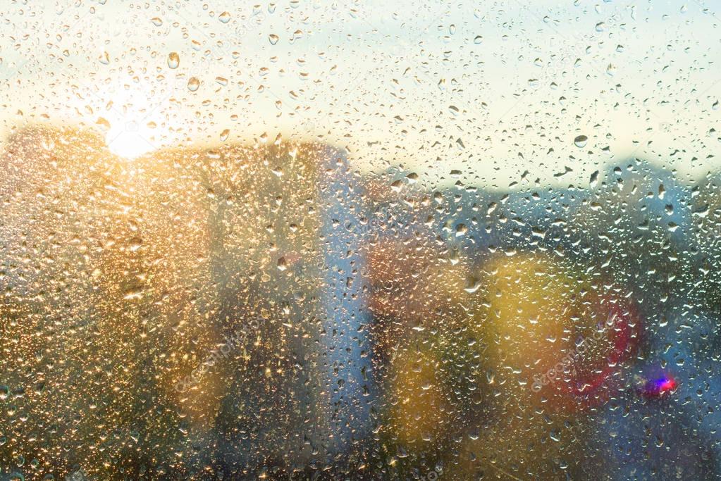 Background sunny window with shiny rain drops, view of the modern city. Abstract texture.