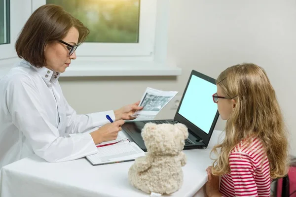 Kvinnliga tandläkare ortodontist med röntgen som pratar med ett barn. — Stockfoto