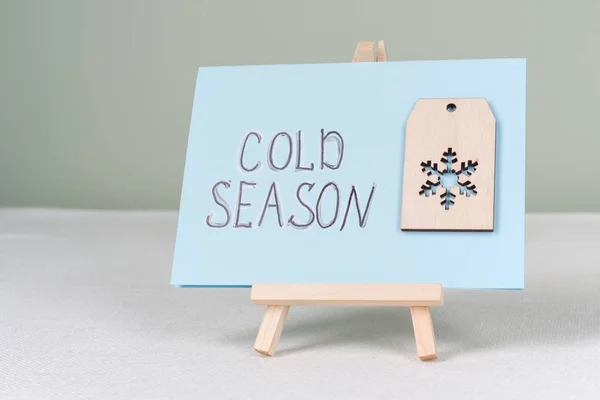 Stagione fredda testo su una cartolina con un fiocco di neve simbolico — Foto Stock