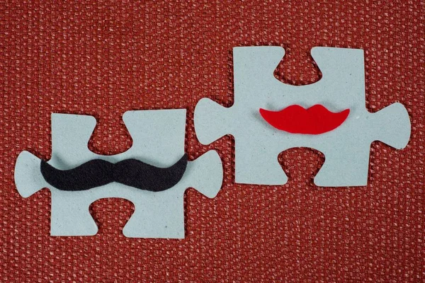 Primo piano di 2 pezzi di un puzzle. Un uomo simbolico coi baffi e una donna con le labbra. Il concetto di compatibilità psicologica — Foto Stock