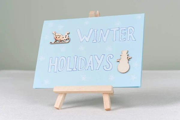 Vacanze invernali - un biglietto di auguri simbolico con pupazzo di neve e slitte — Foto Stock