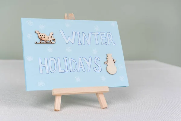 Vacanze invernali - un biglietto di auguri simbolico con pupazzo di neve e slitte — Foto Stock