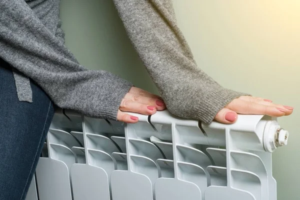 Vrouw legde haar handen op de radiator — Stockfoto