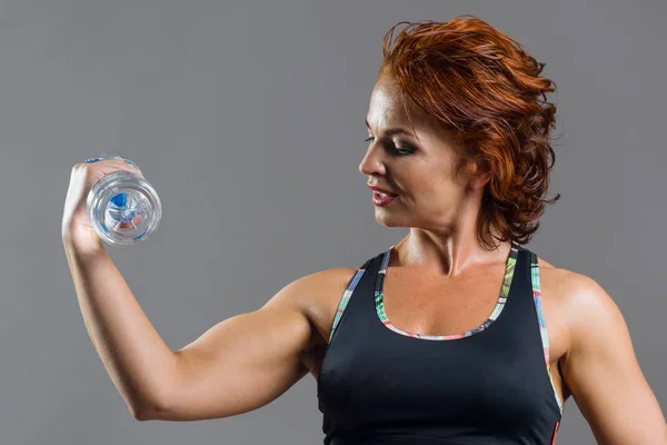 Ενηλίκων αθλητικό γυμναστήριο Κοκκινομάλλης γυναίκα σε ομοιόμορφο με ένα μπουκάλι νερό σπορ — Φωτογραφία Αρχείου