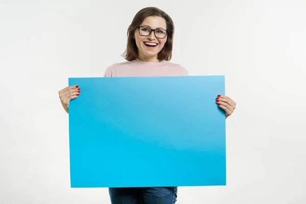 Smiling middle aged woman with blue sheet billboard — Stock Photo, Image