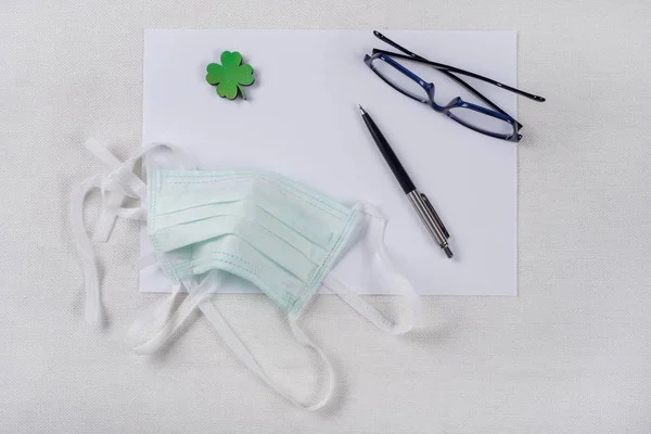 O conceito de ecologia, proteção da natureza. Fundo - papel limpo, folha de trevo verde e uma máscara protetora . — Fotografia de Stock