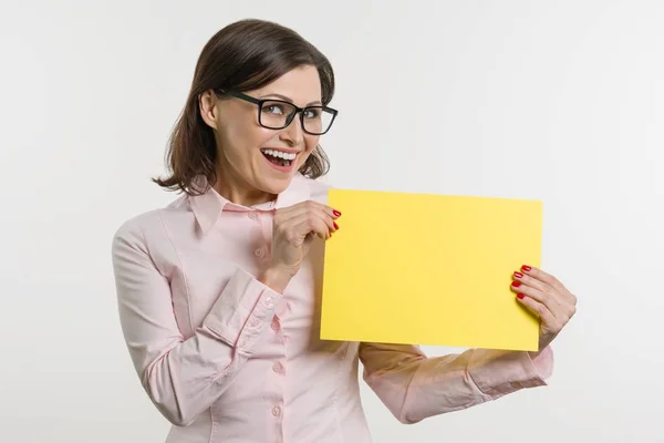 Улыбающаяся женщина средних лет с желтым листом бумаги — стоковое фото