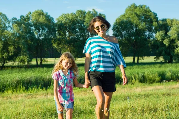 Kvinna med dotter barn promenader i naturen håller händerna. — Stockfoto