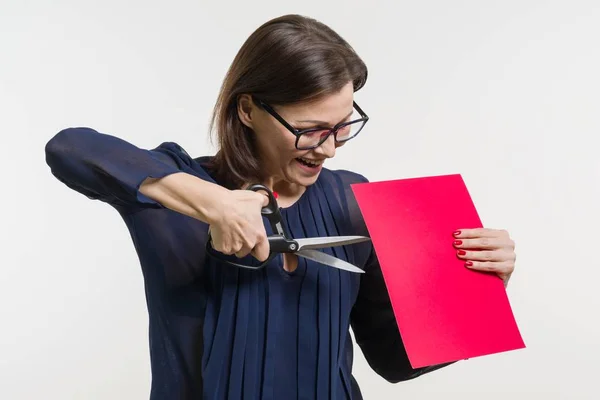 Женщина держит ножницы и лист бумаги, режет бумагу . — стоковое фото