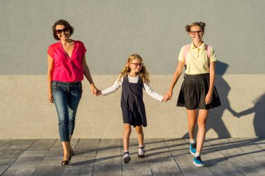 Bir mutlu sevgi dolu aile - anne ve kızı bir kız öğrenci, el ele tutuşarak.
