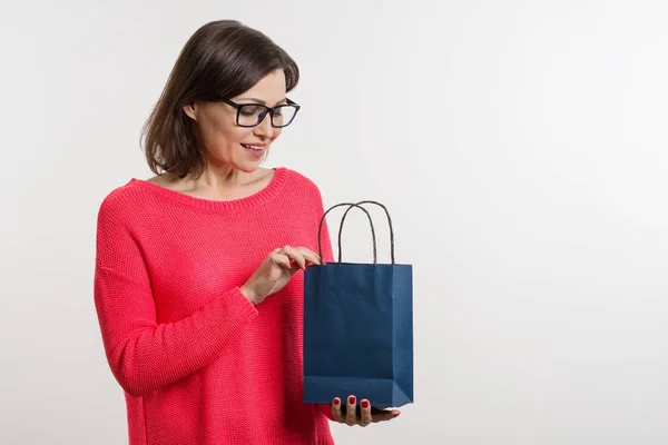 Frau mittleren Alters öffnet eine Einkaufstasche, weißer Hintergrund — Stockfoto