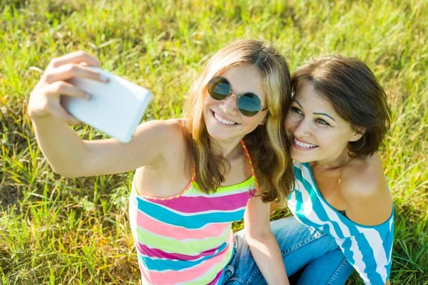 Mom and daughter teen together. Do selfie on the phone.