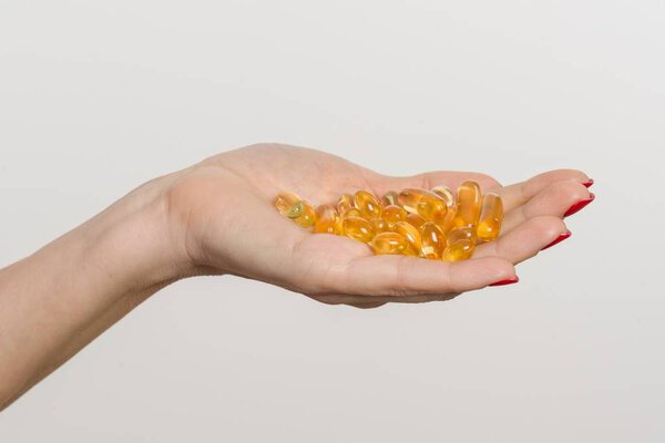 Hand holding capsule Omega 3 on white background