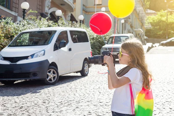 Felice turista bambina. Con una fotocamera, palloncini, uno zaino — Foto Stock