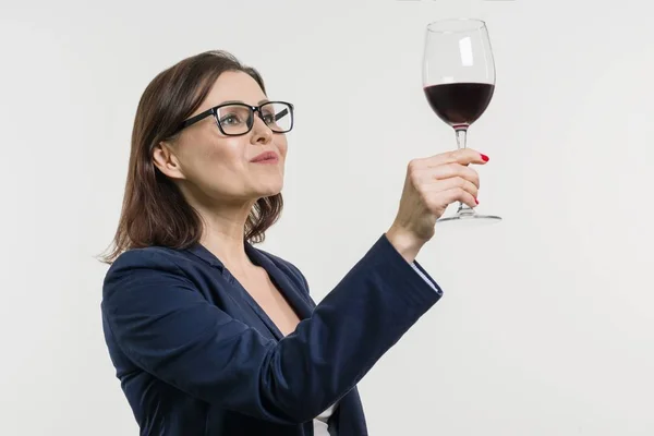 İş kadını tutarak ve bir kadeh kırmızı şarap seyir. — Stok fotoğraf