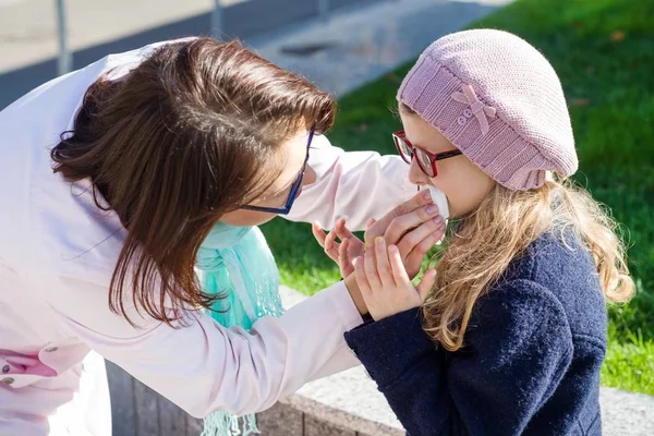 Moeder dochter mond met een papieren zakdoekje veegt. — Stockfoto