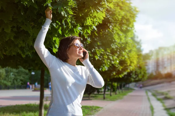 Stilig leende kvinna med mobiltelefon promenad på gatan — Stockfoto