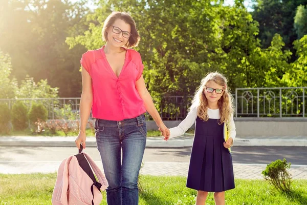 Mom and pupil of elementary school  holding hands. — Stock Photo, Image