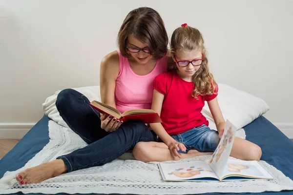 Mujer feliz con su hija, leyendo juntos un libro a —  Fotos de Stock