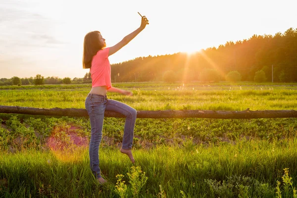 Tini lány csinál selfie, sunset háttér telefon. — Stock Fotó