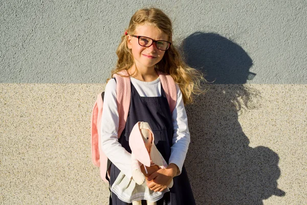 Una linda colegiala de la escuela primaria está sonriendo, sosteniendo un juguete . —  Fotos de Stock