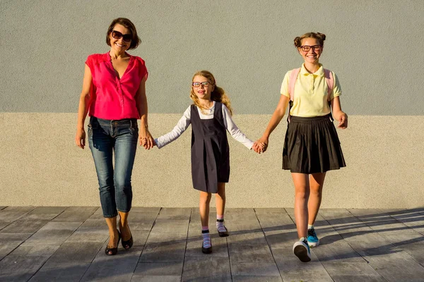 Счастливая семья - мама и сестры школьницы держатся за руки . — стоковое фото