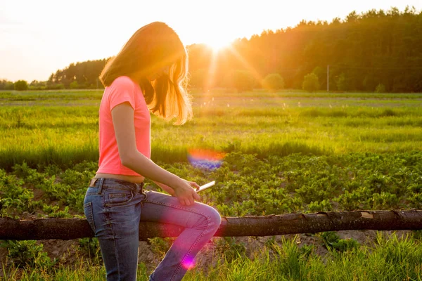 Barn i bakgrunden av naturen spela med en smartphone. — Stockfoto