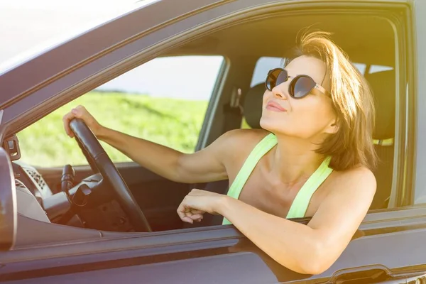 Vrouwelijke bestuurder glimlachen tijdens het rijden zijn auto — Stockfoto