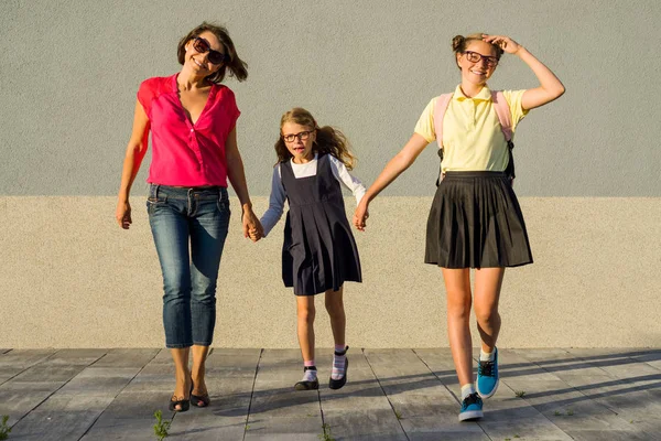 ครอบครัวที่มีความสุข แม่และน้องสาว เด็กนักเรียนจับมือกัน . — ภาพถ่ายสต็อก