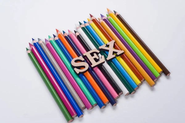 Un cuvânt sex litere abstracte, creioane de fundal alb colorate — Fotografie, imagine de stoc