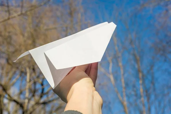Abstract paper plane in hand, blue sky, spring trees sun background — Stock Photo, Image