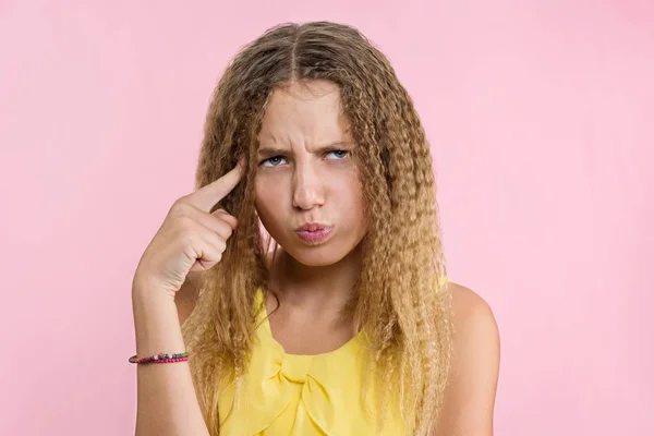 Adolescente rubia con el pelo rizado frunciendo el ceño, frunciendo el ceño mientras mira hacia otro lado con mirada tranquila y reflexiva . — Foto de Stock