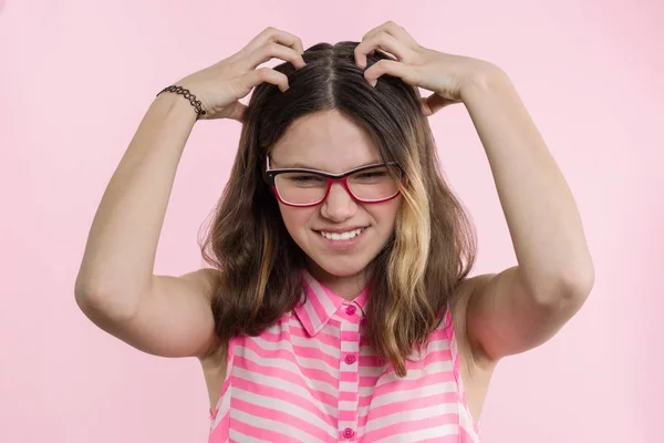 Chica adolescente con gafas, con el pelo largo se rasca la cabeza y es emocional desconcertado . — Foto de Stock