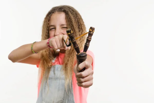 Nastolatek Niegrzeczna dziewczynka z kręconymi włosami posiada procy. — Zdjęcie stockowe