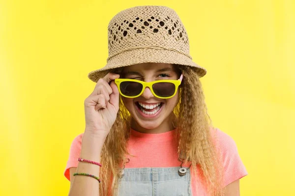 Musim panas waktu, seorang gadis remaja di topi jerami dan kacamata hitam mengedipkan mata atas latar belakang kuning . — Stok Foto