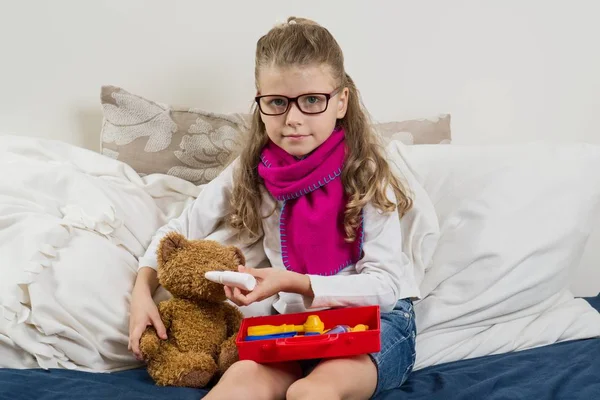 Ένα άρρωστο παιδί κορίτσι με τα γυαλιά, θεραπεύει τον άρρωστο αρκουδάκι — Φωτογραφία Αρχείου