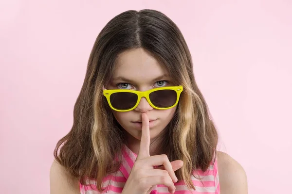 Chica adolescente seria 13,14 años en gafas de color amarillo brillante muestran signo de silencio — Foto de Stock