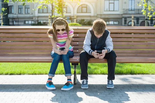 Niños y niñas adolescentes juegan, leen, miran el teléfono inteligente . —  Fotos de Stock