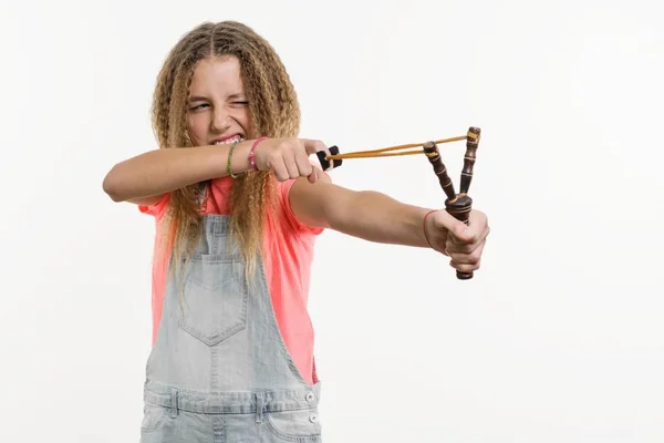 Menina safada adolescente com cabelo encaracolado detém um estilingue. Estúdio fundo branco — Fotografia de Stock