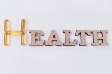 E vitamini takviyesi. Word sağlıktır soyut ahşap harf ve balık yağı kapsülleri