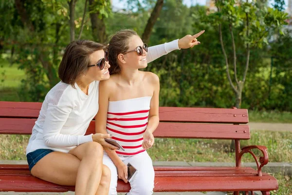 Επικοινωνία μεταξύ γονέα και παιδιού. Μαμά και κόρη έφηβος μιλώντας και γελώντας ενώ κάθεται στον πάγκο στο πάρκο — Φωτογραφία Αρχείου