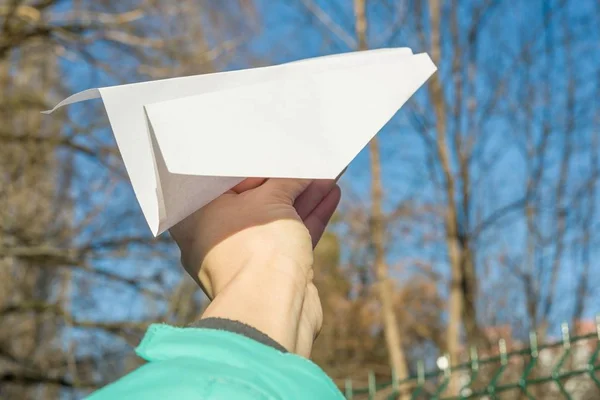 Abstracte papier vliegtuig, in de hand, de blauwe hemel, de zon voorjaar achtergrond. — Stockfoto