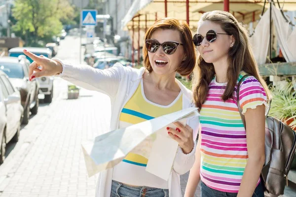 Mom and daughter teenager tourist looking at the map on the street of city. — Stock Photo, Image