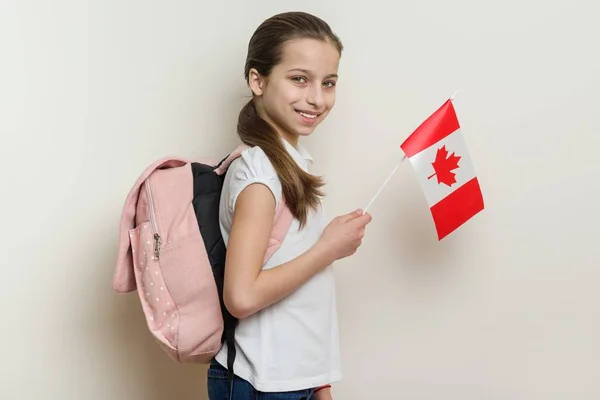 Studentessa 10 anni in T-shirt bianca con uno zaino che tiene la bandiera del Canada — Foto Stock